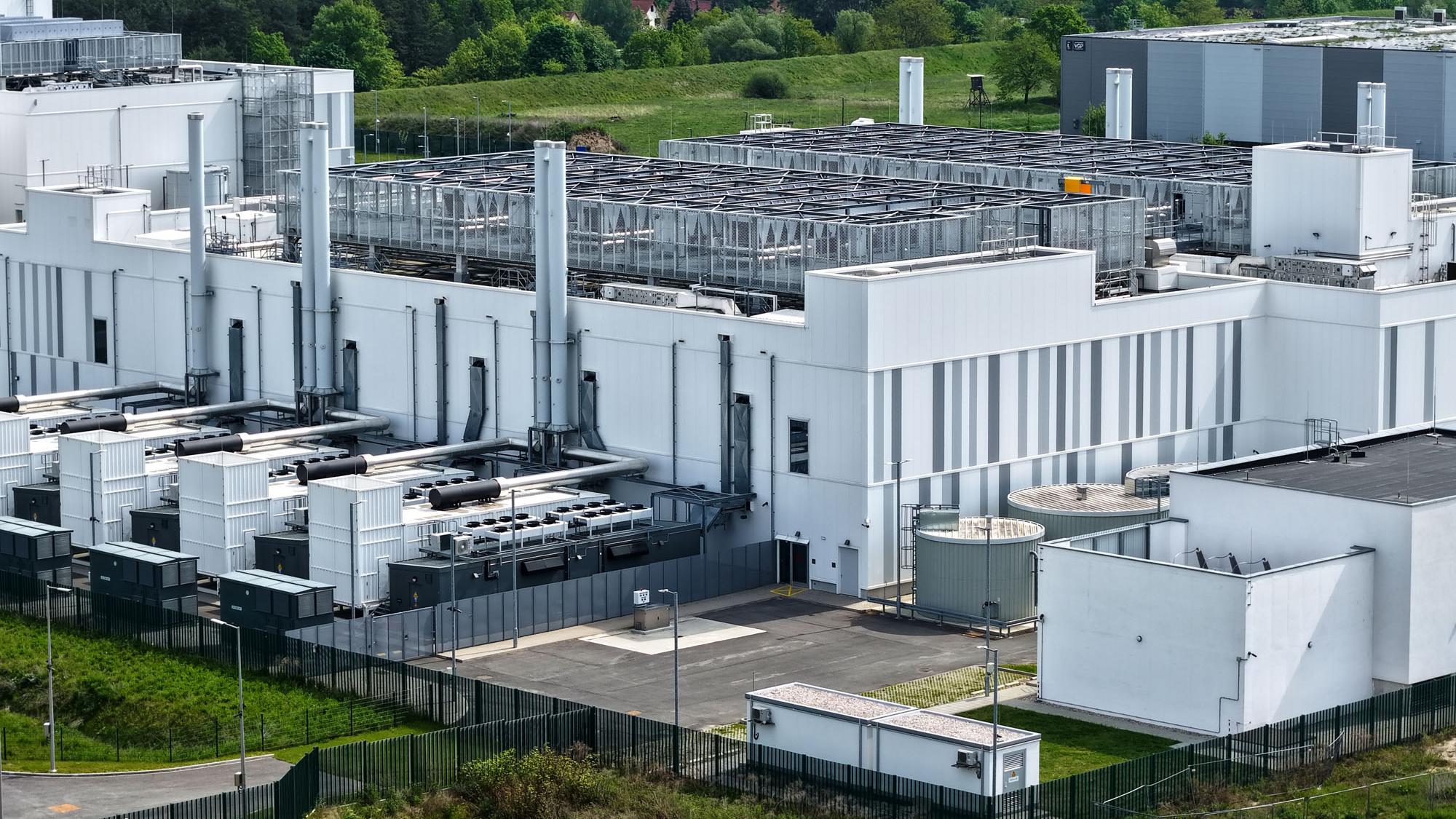 An aerial photo showcasing a large data center facillity, with many cooling units, pieces of piping, and other pieces of technical infrastructure visible