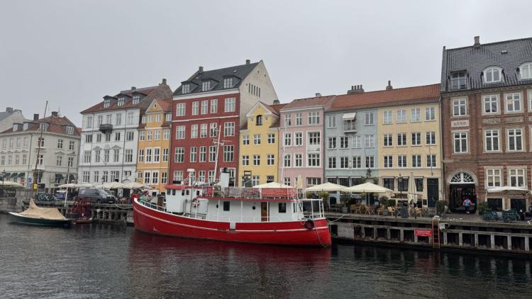 a view of copenhagen, denmark, from a canal with a boat in front of the pier.