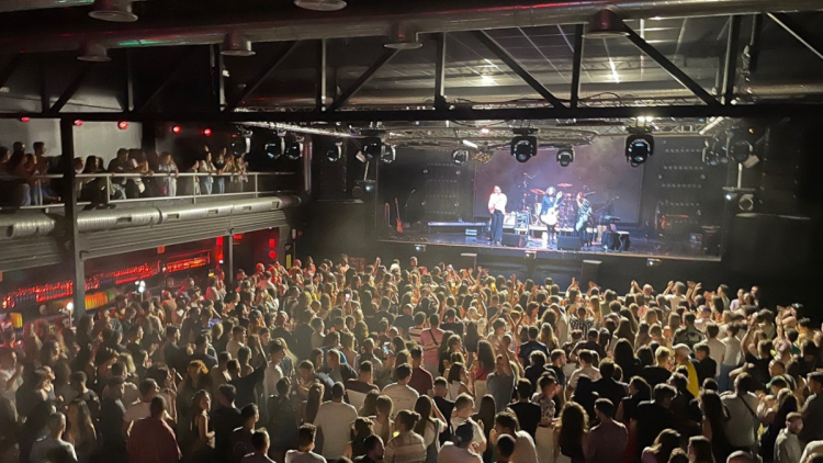 View of a band playing on a stage at a concert with an audience watching