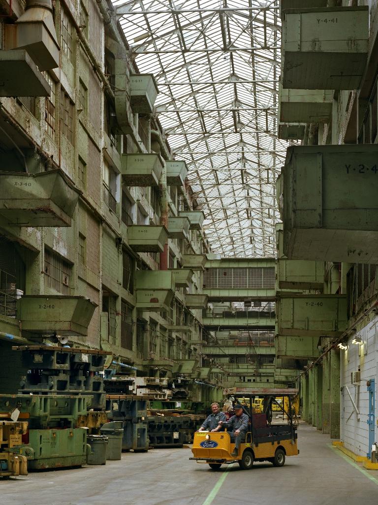 Two men pose in a work vehicle at a Ford plant in Detroit.