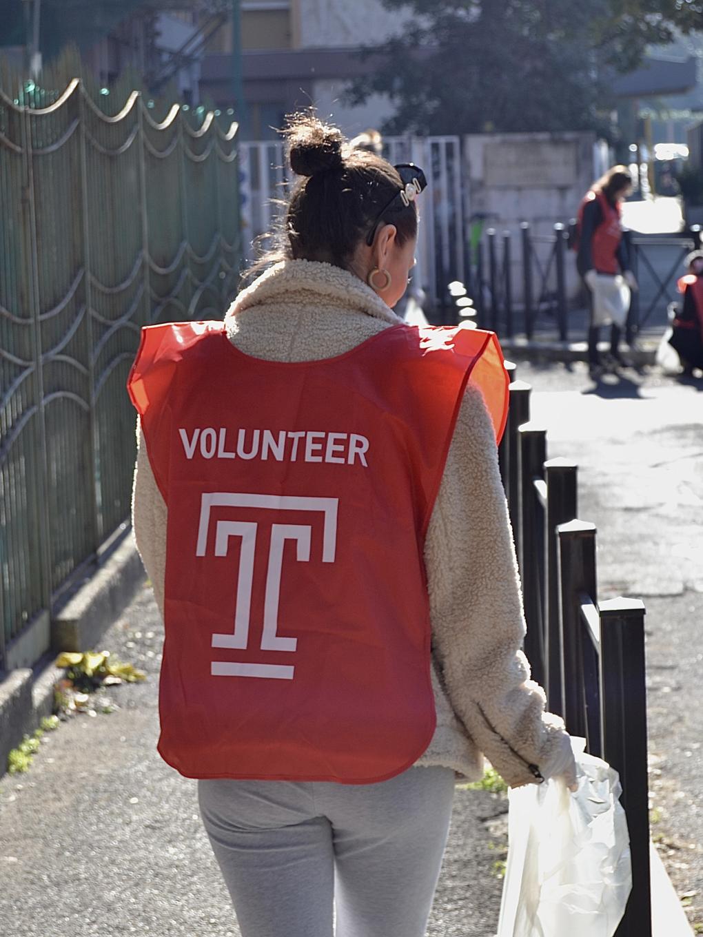 A student in a Temple overshirt cleaning up a street