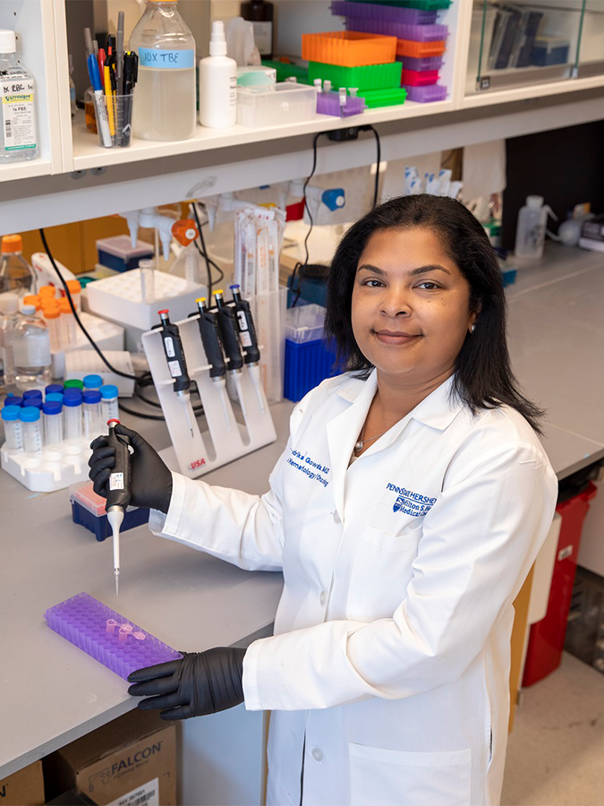 Scientist in a white lab coat holding a pipette