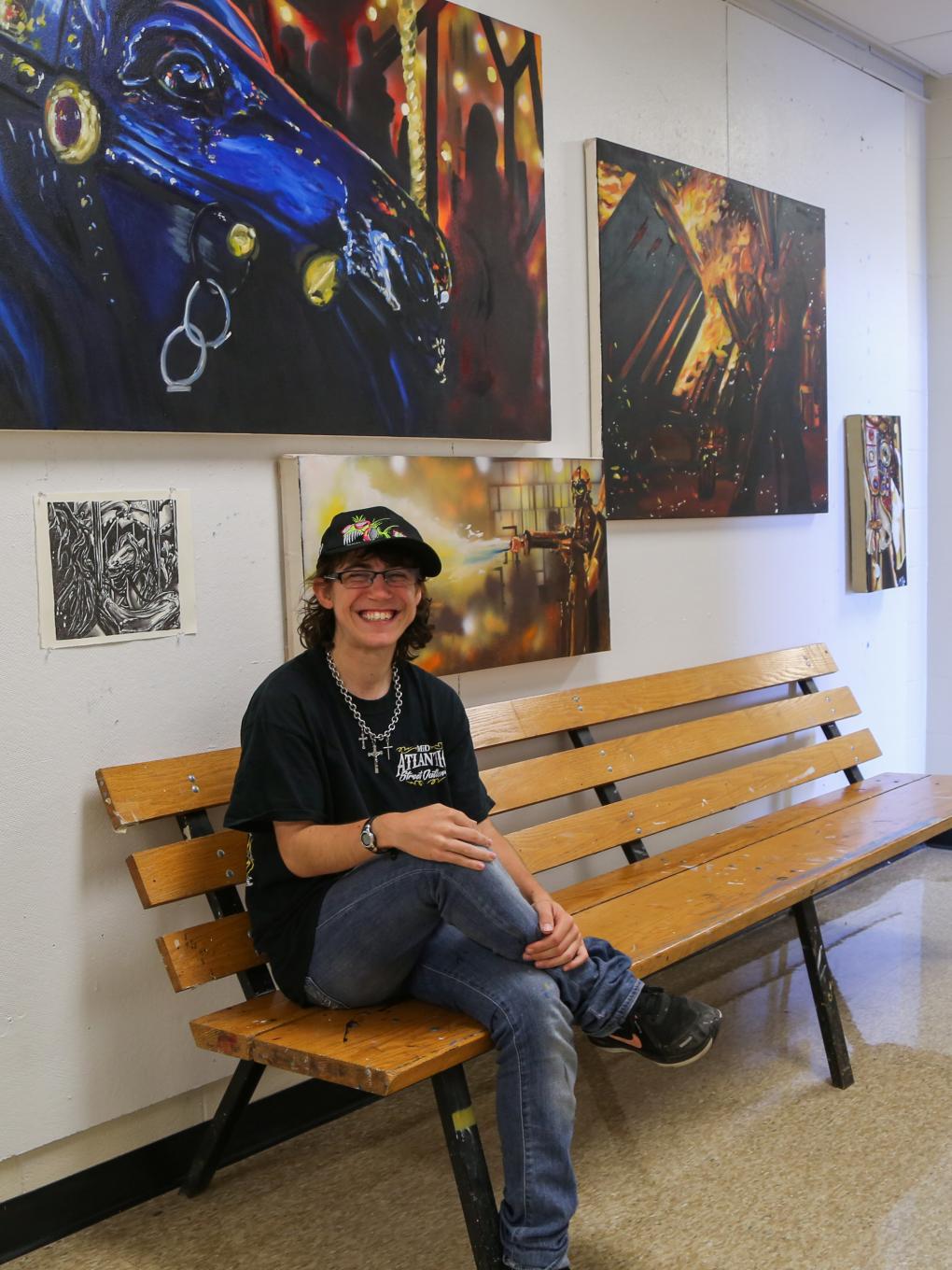 Taylor Bielecki sits below her paintings. 