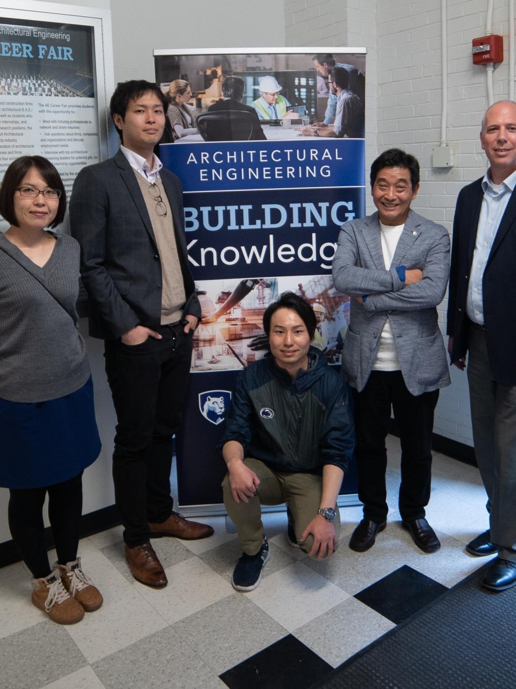 Men and women posing for a photo in front of an architectural engineering sign