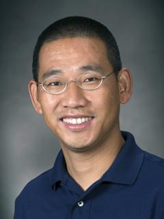 male professor in business attire smiles and poses for professional headshot photo