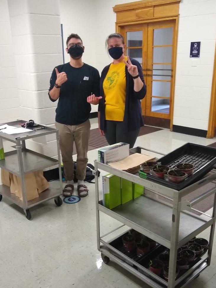 Two people posing for a photo with carts with lab equipment