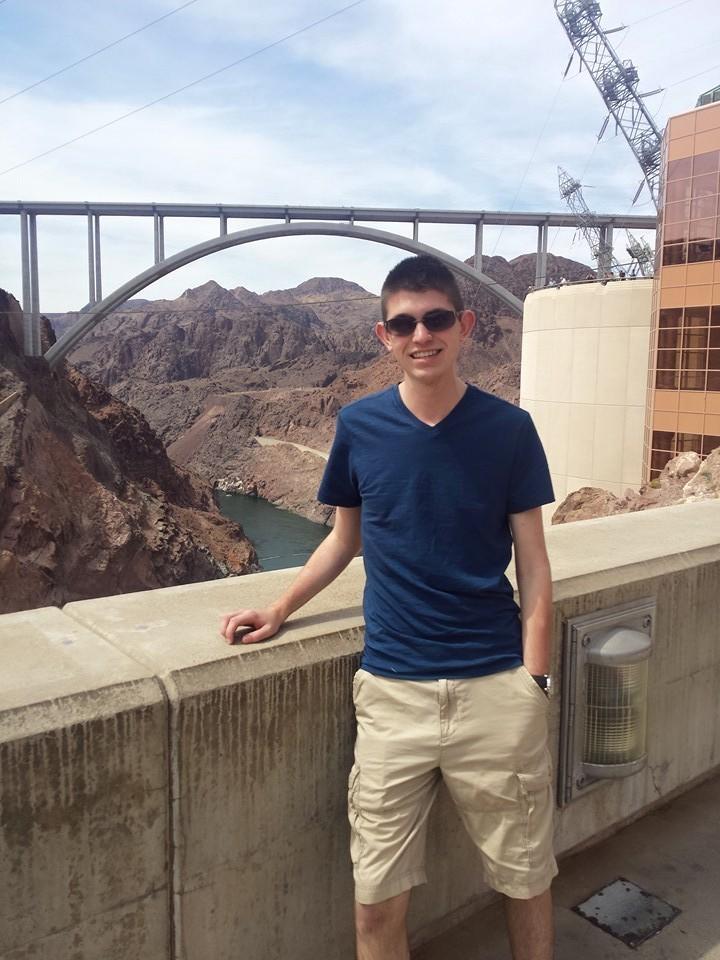 student standing on a dam with bridge in background