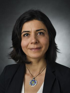 Professor in business attire smiles and poses for professional headshot photo