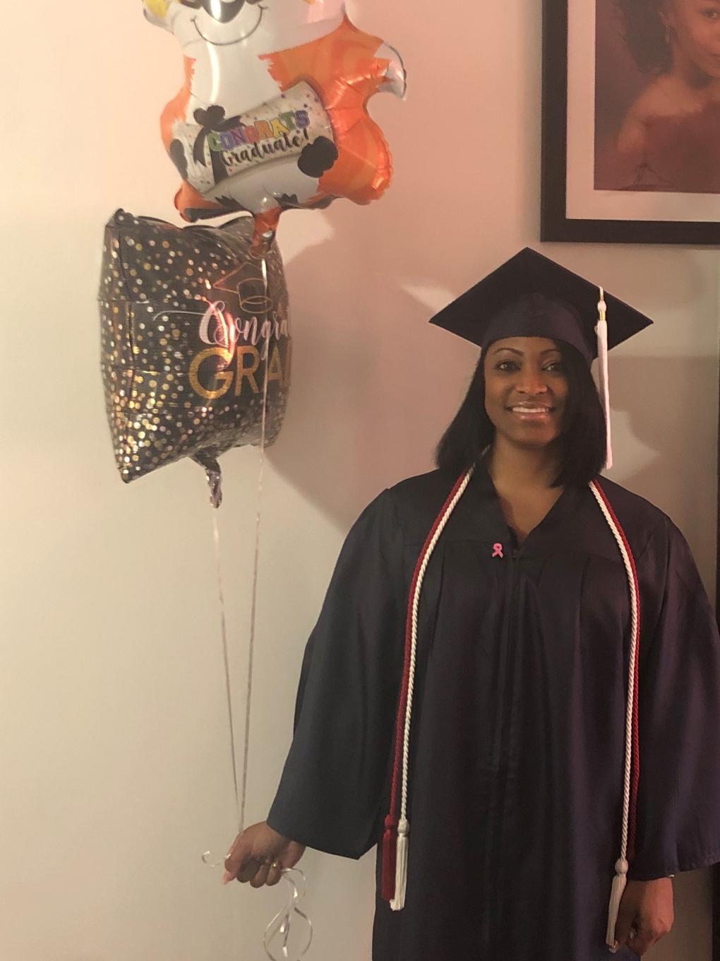 graduate in cap and gown holding balloons