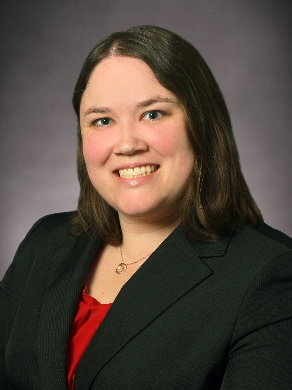 Woman dressed in business attire, smiles for a professional headshot