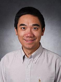 A headshot of a man in a striped button-down shirt