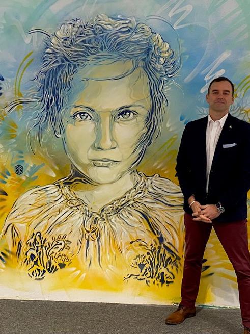 A man standing in front of a colorful painting of a child