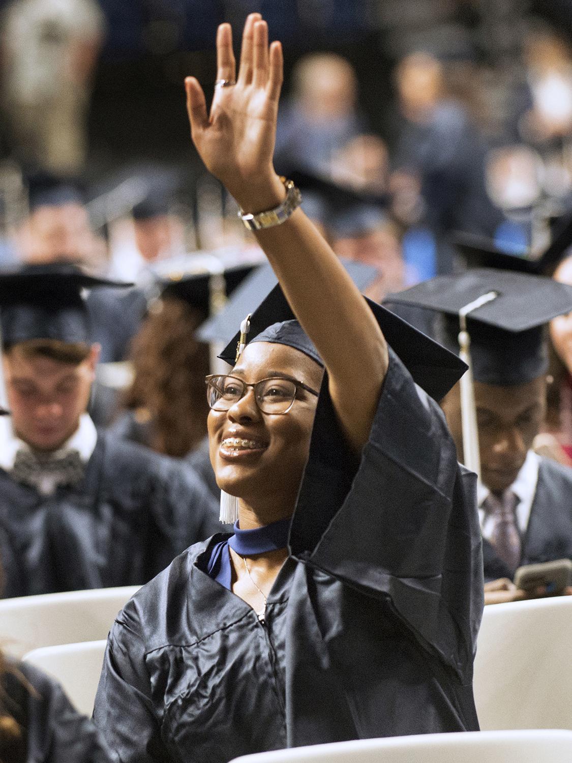 A graduate waves at Penn State commencement.