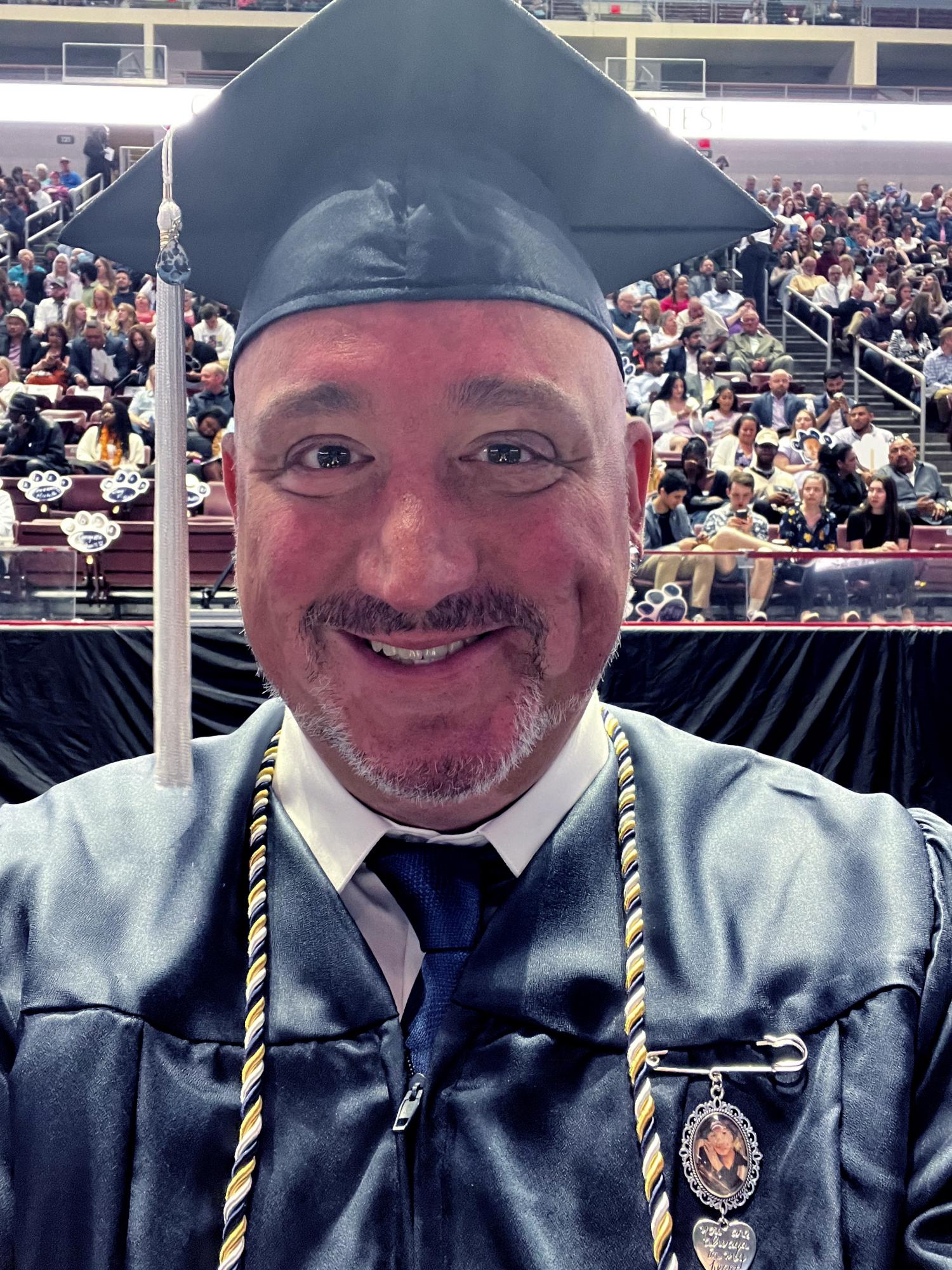 a man wearing a graduation cap and gown in front of stands in an arena