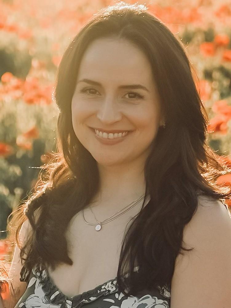 Latina with dark hair and a sun dress smiling in a shaft of sun light