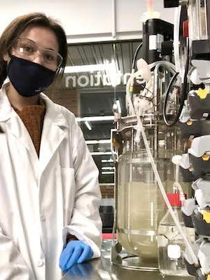 Mia Vega posing in lab uniform and protective gear inside laboratory
