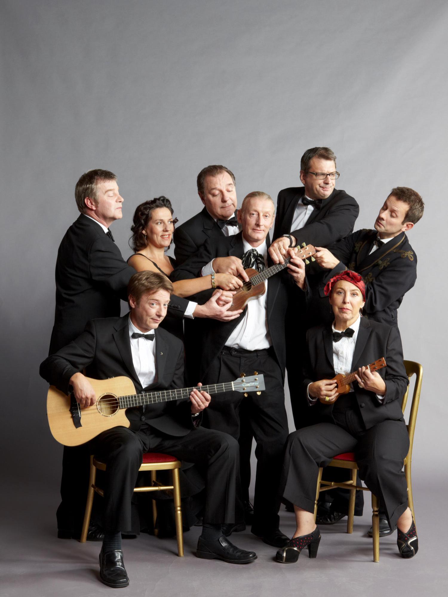 The eight members of the Ukulele Orchestra of Great Britain pose with their instruments.