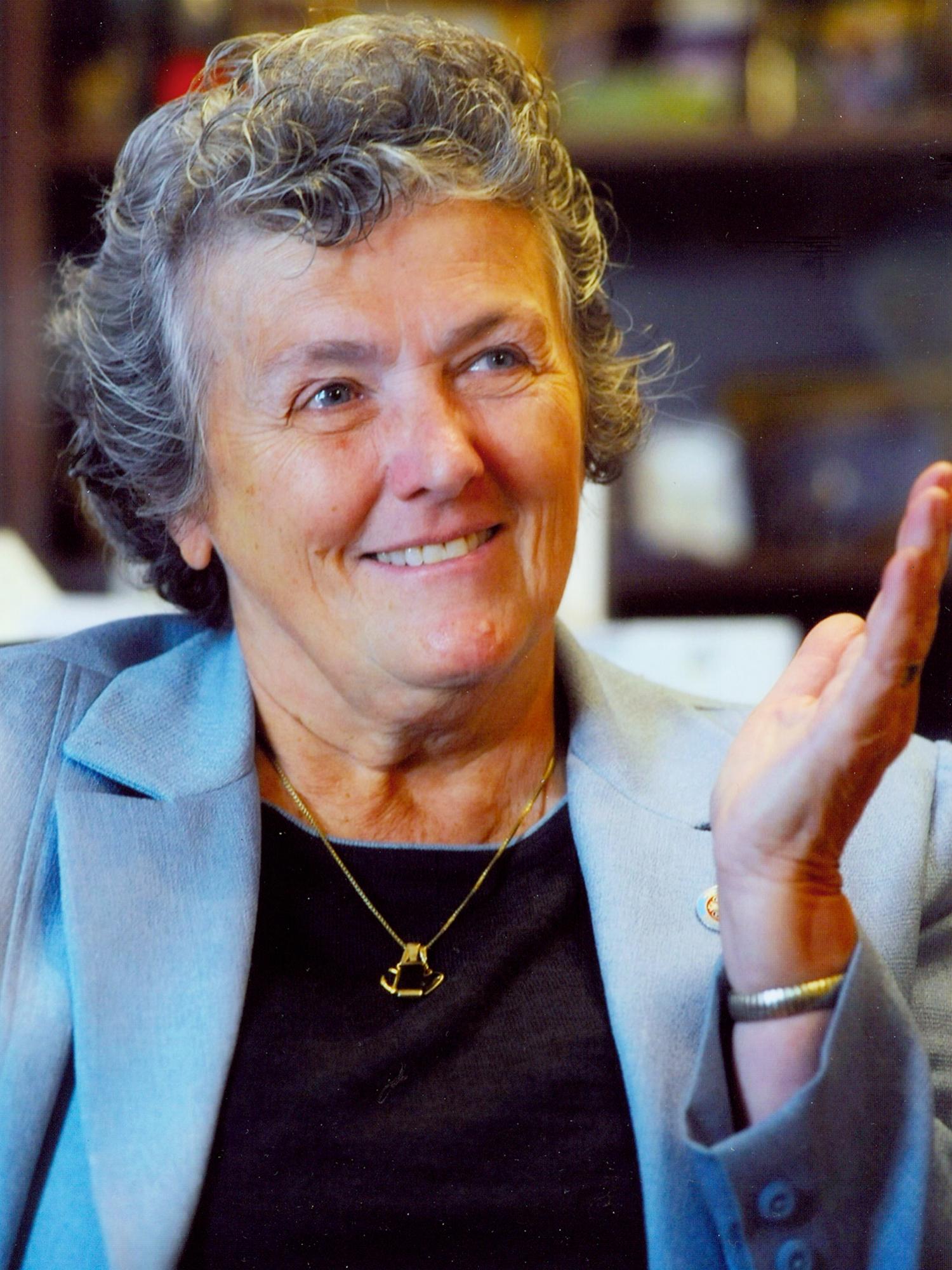 vertical portrait of Sister Joan Chittister, smiling, wearing light blue suit jacket and black blouse