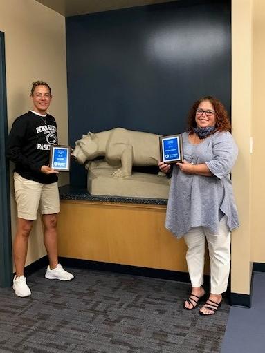 two women holding awards