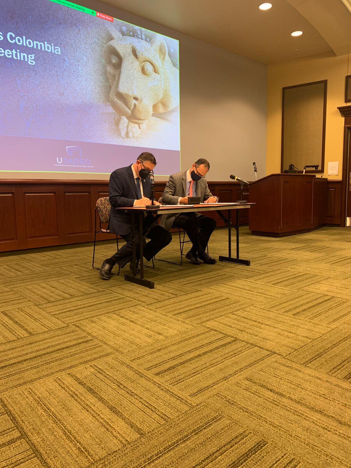 Two men sitting at a table signing