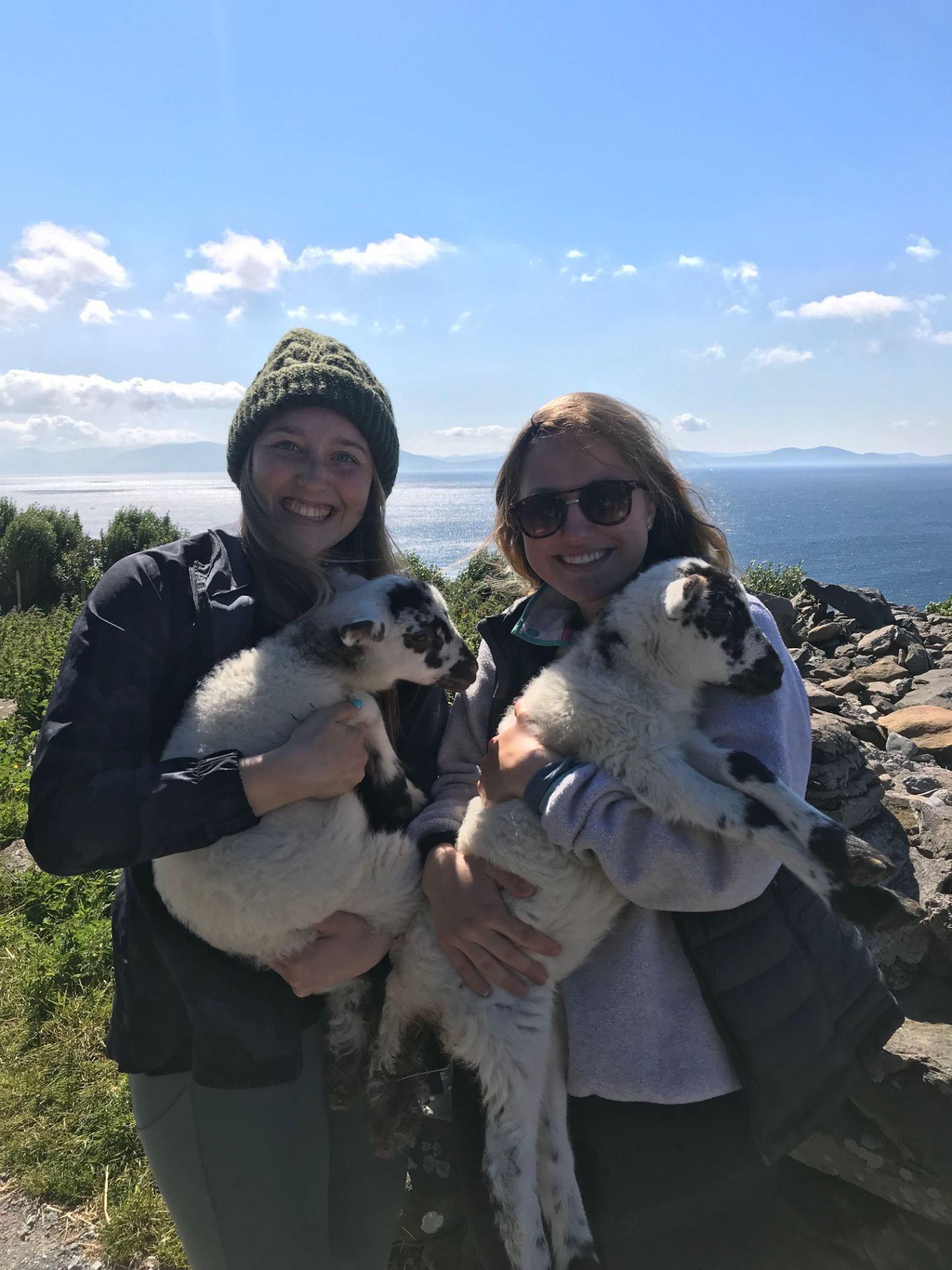 Two girls holding lambs 