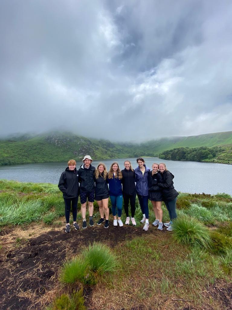 A group of 8 pose in front of a lake 