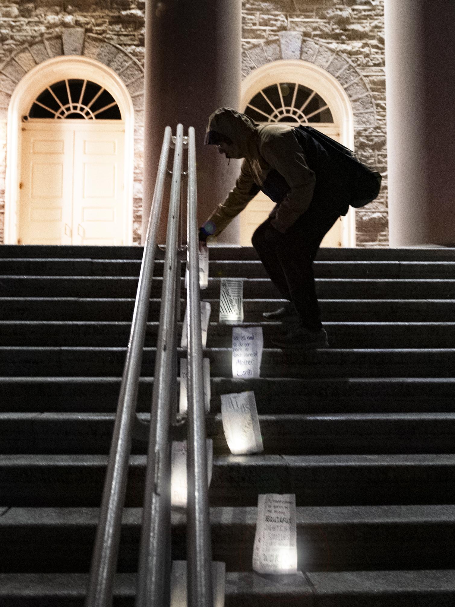 student places candle bag at Old Main