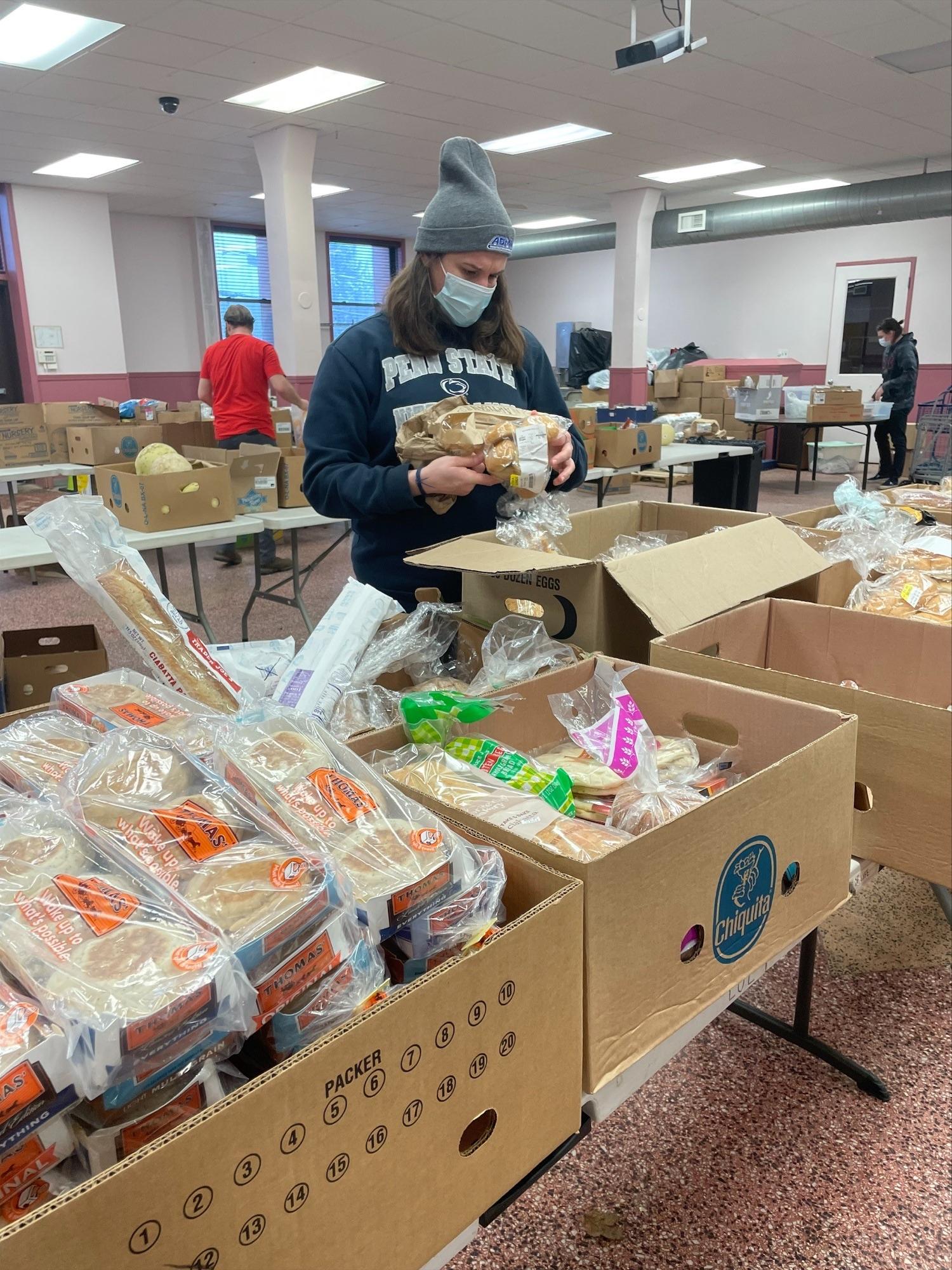 Student checking expiration dates on food at a food pantry