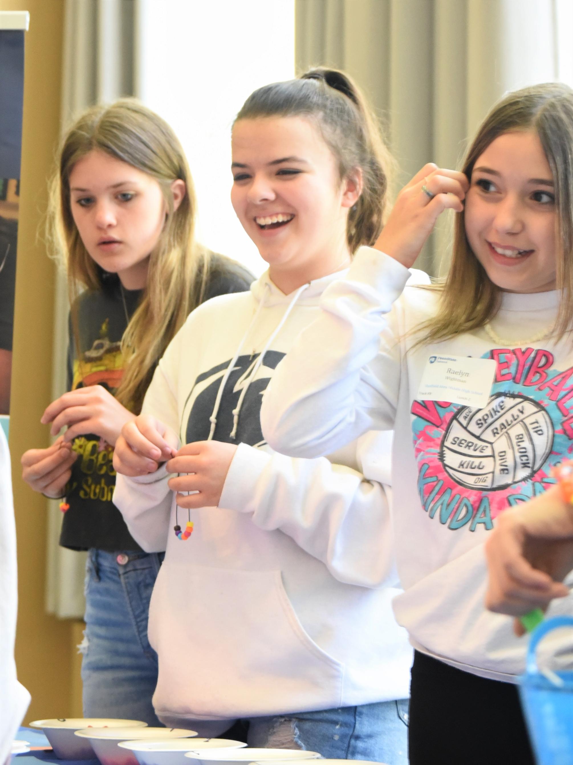 Three female middle-school students make beaded bracelets at Penn State Behrend's Math Options Career Day.