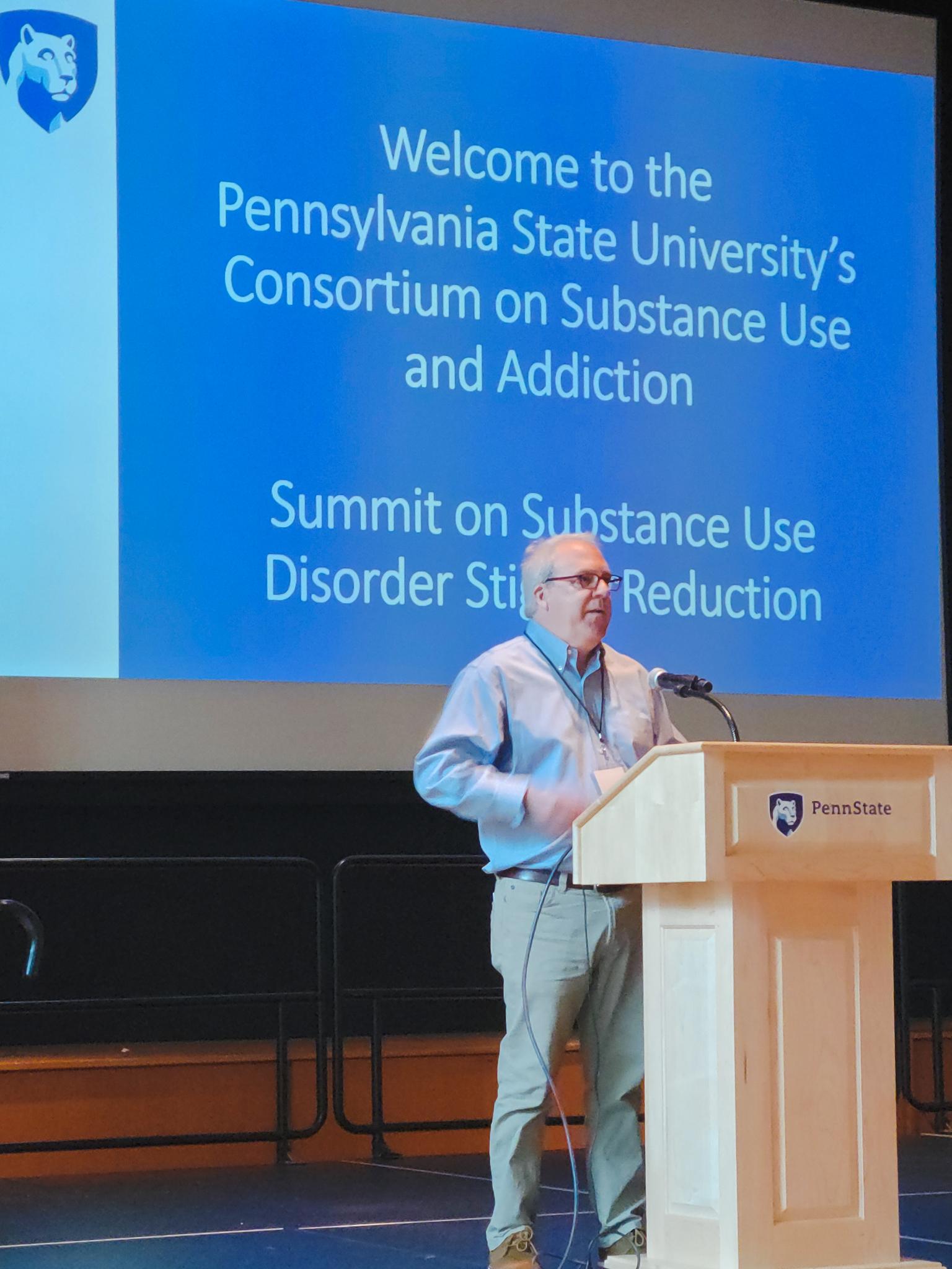 Paul Griffin, a white man in a blue collared shirt standing at the podium.