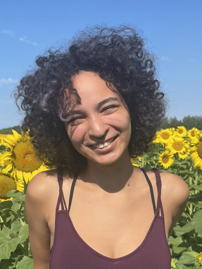Ziyen Curtis stands in a field of sunflowers.