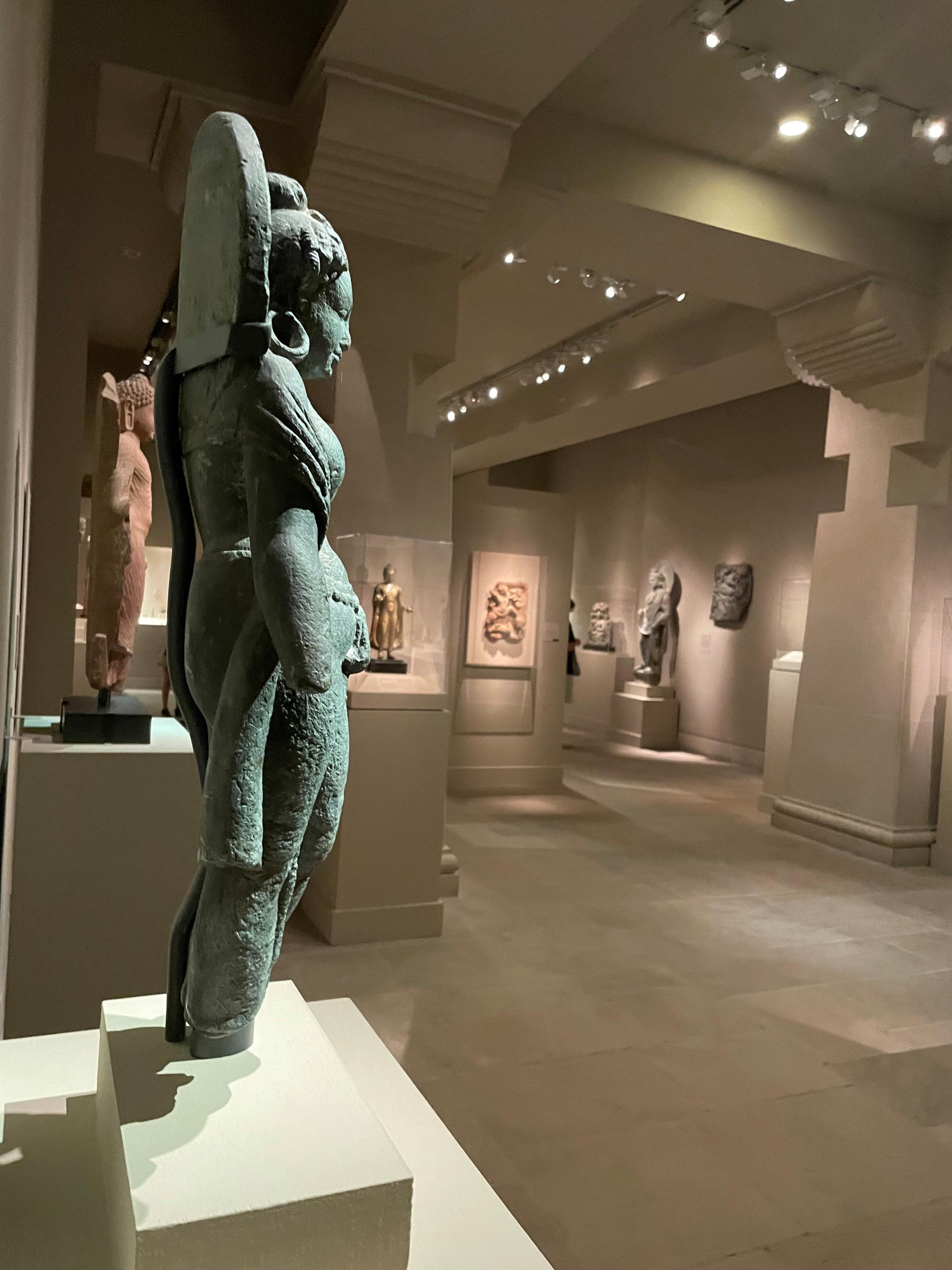 A sculpture depicting a mother goddess figure is displayed in a museum