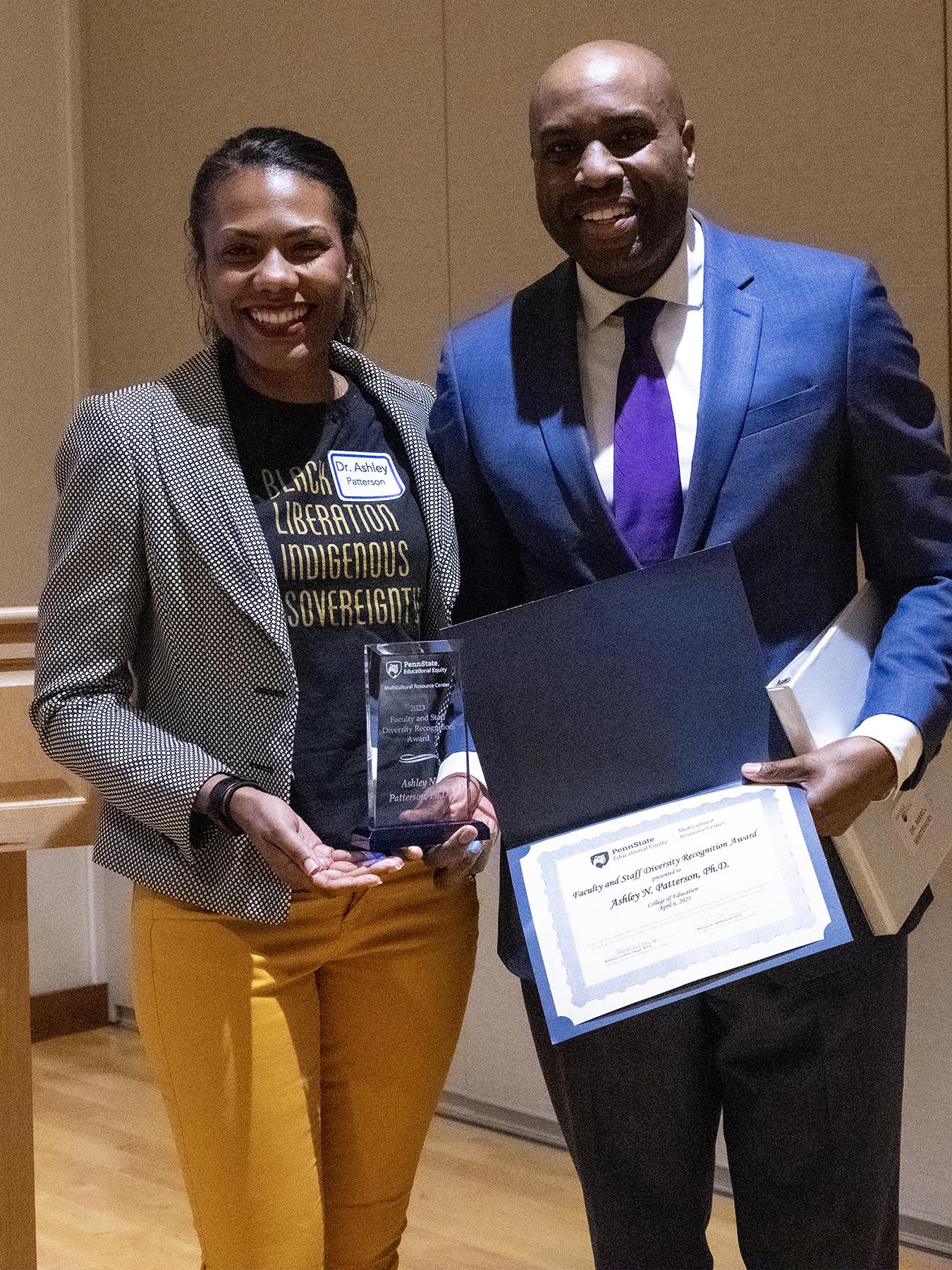 Woman on left holding award she was presented by man on right