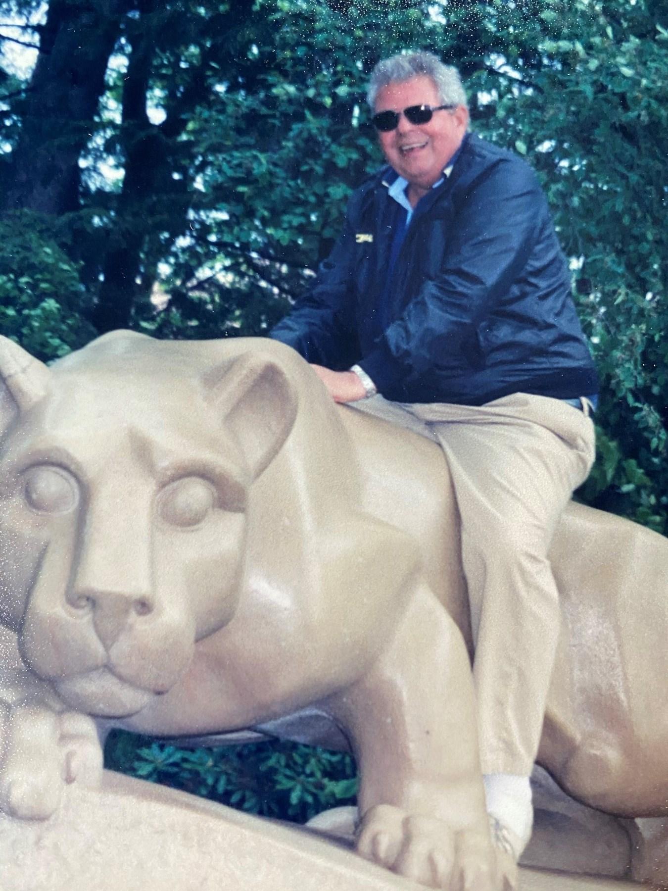 person wearing sunglasses sits atop lion statue