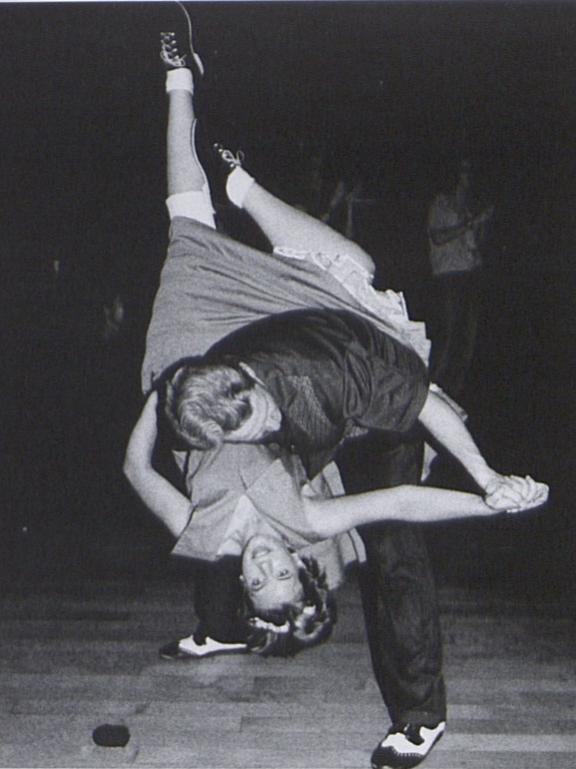 A male student dips a female student during swing dance practice