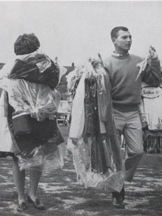 A male student and a woman carry armfuls of clothing