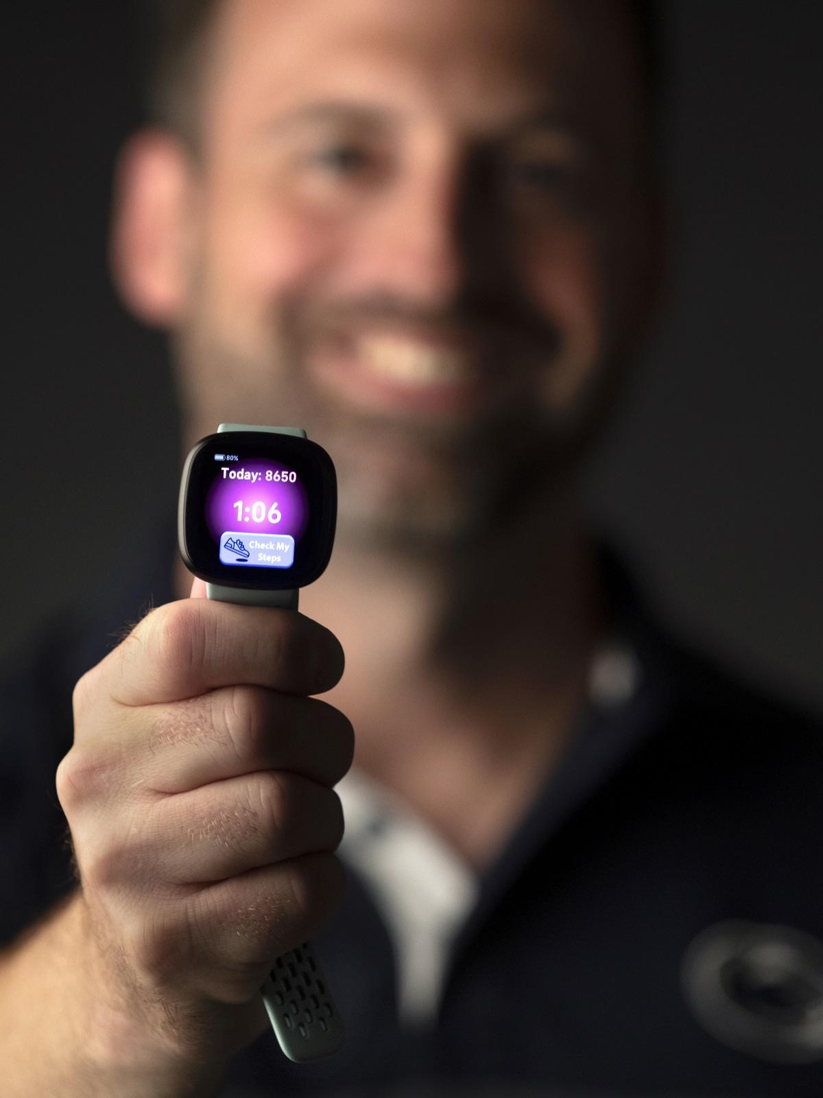 A man holds a smart watch that reads "80% power, Today: 8650, 1:06 and a button reads: "check my steps.""