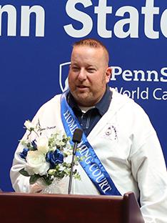 A man stands at a podium in front of a blue background.