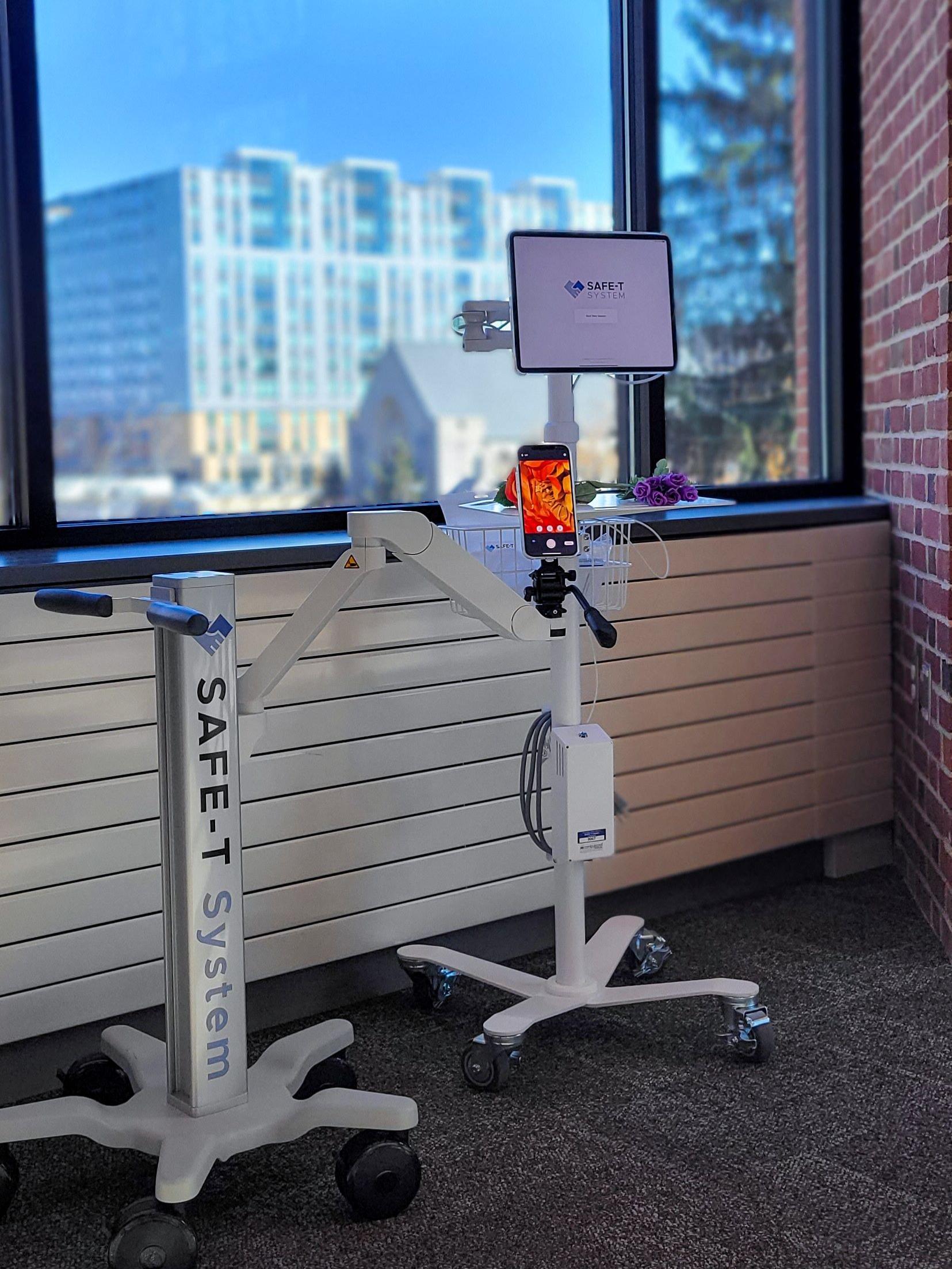 The telehealth equipment developed by the SAFE-T System team posed in front of large glass windows.