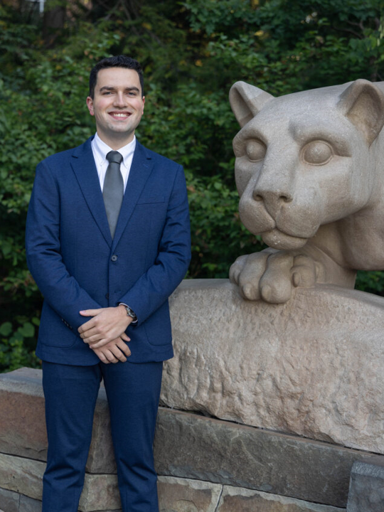 Brandon Bixler standing next to lion statue