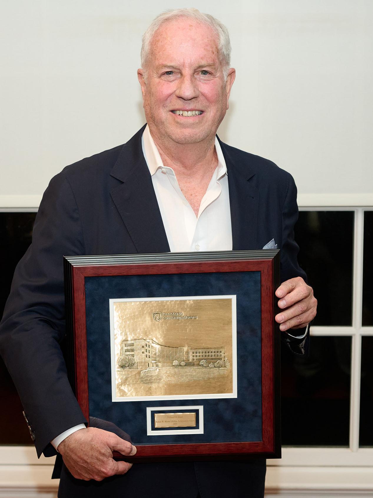 Richard Bard poses with a plaque presented to him by the Penn State Smeal College of Business that recognizes him with the Robert W. Moore Lifetime Achievement Award.