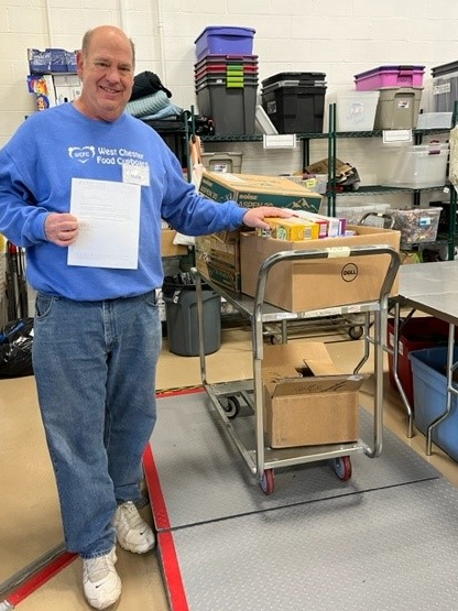 A man stands next to food donations