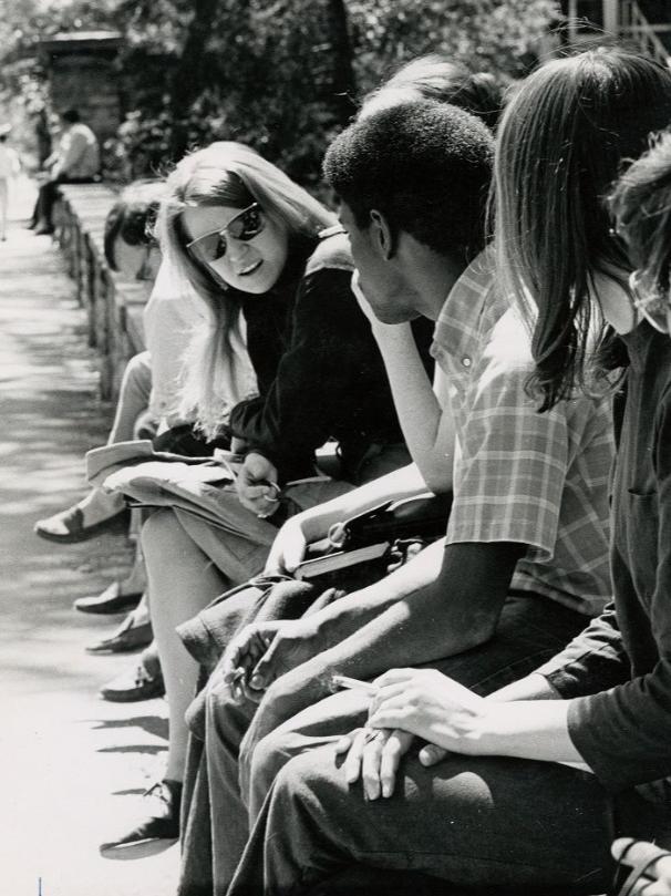 A group of students sit on a stone wall