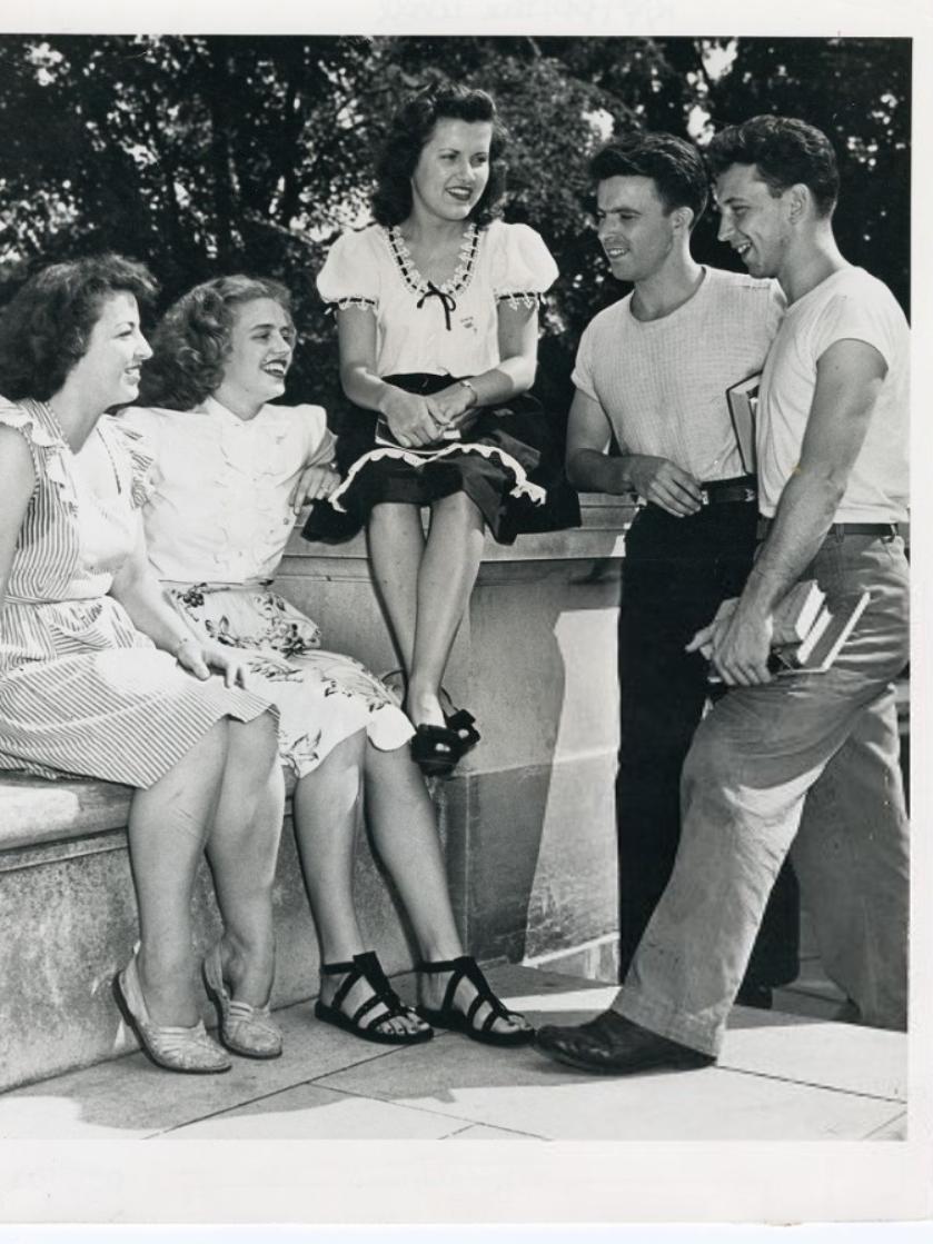 A group of students sit on a stone wall