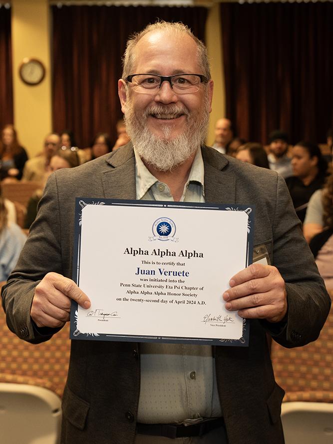 Juan Veruete stands with his Tri-Alpha induction certificate