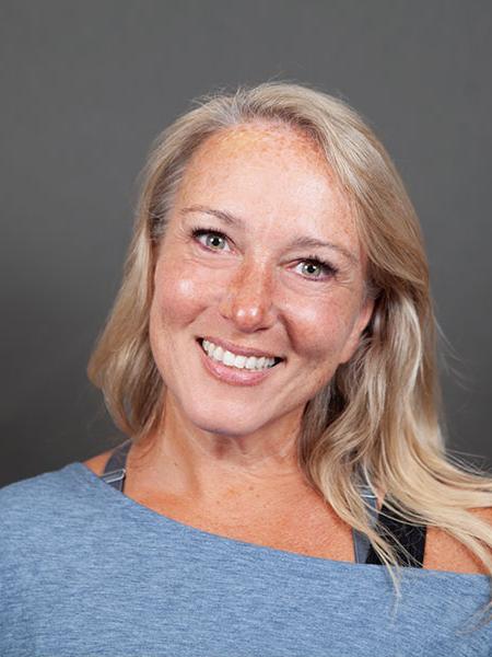 A smiling woman tilts her head to one side.