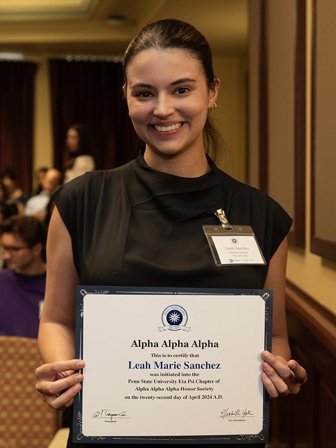 Leah Marie Sanchez stands with her Tri-Alpha induction certificate