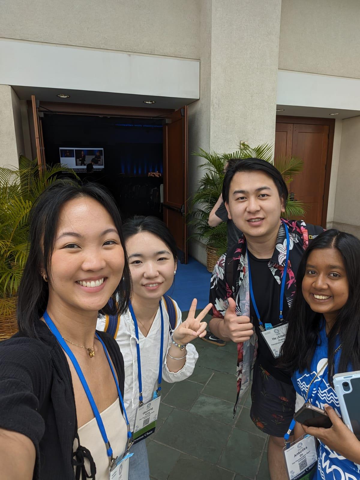 four people wearing lanyards in front of conference room