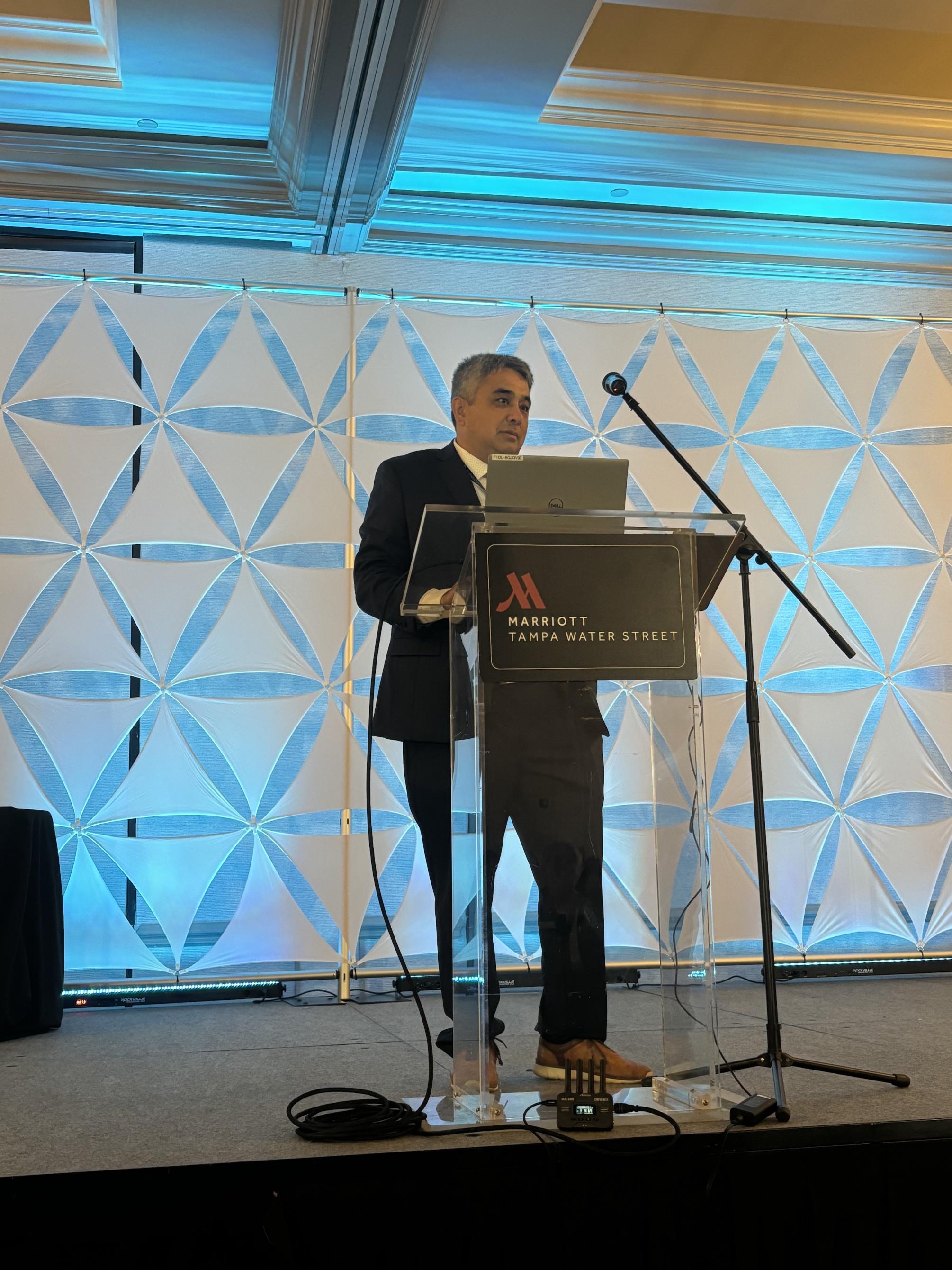 Person stands at a podium speaking into a microphone