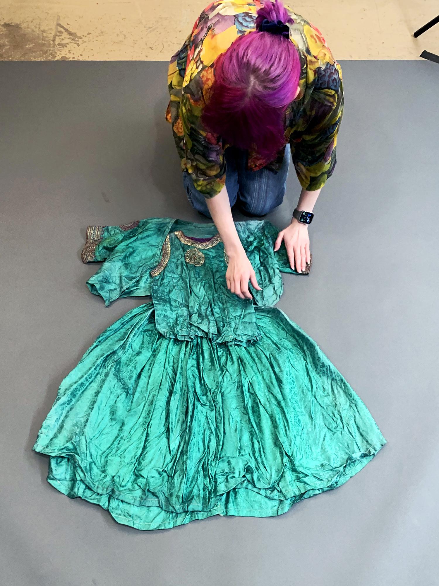 A student arranges a child's dress for photographing
